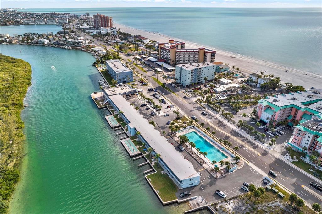 An aerial view shows a coastal hotel with a swimming pool along a waterway — 18399 GULF BLVD UNIT 372, INDIAN SHORES, FL