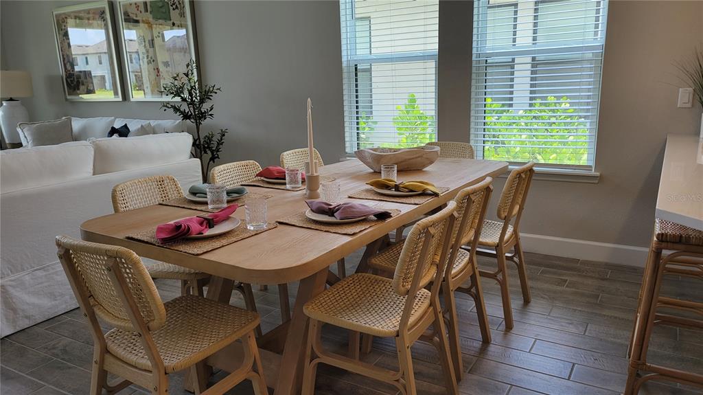 A dining room features a light wood table with woven chairs and large windows — 5419 SUMMIT GLEN, BRADENTON, FL