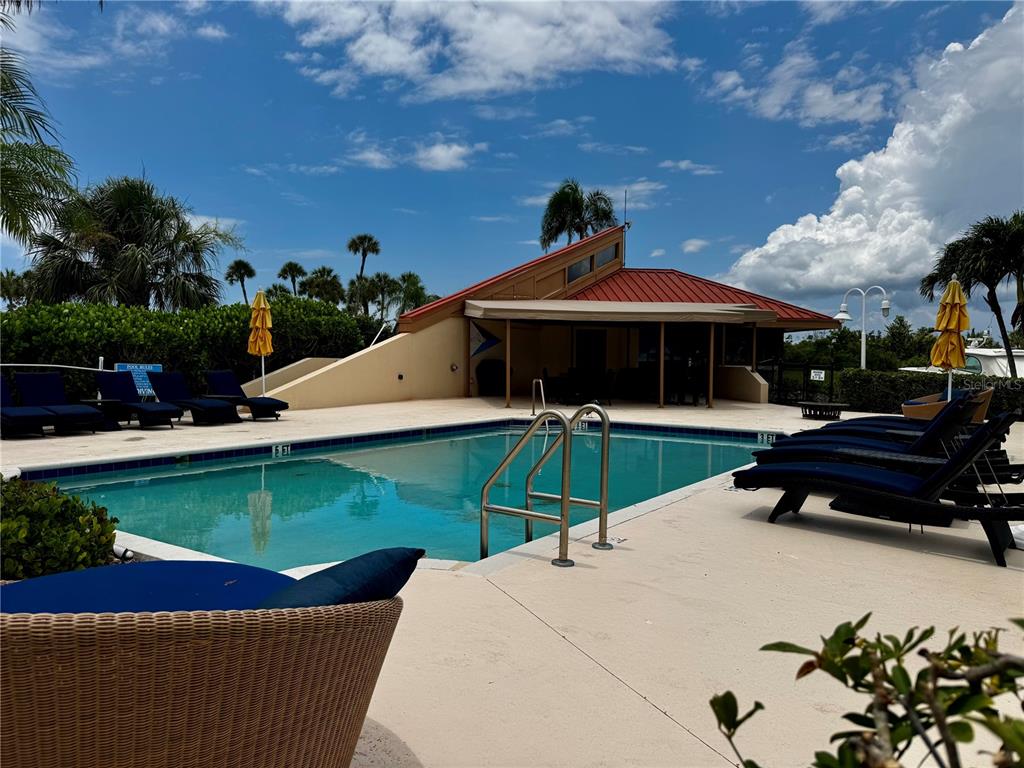 A swimming pool with lounge chairs and a covered patio area under a blue sky — 2600 HARBOURSIDE DRIVE UNIT C11, LONGBOAT KEY, FL