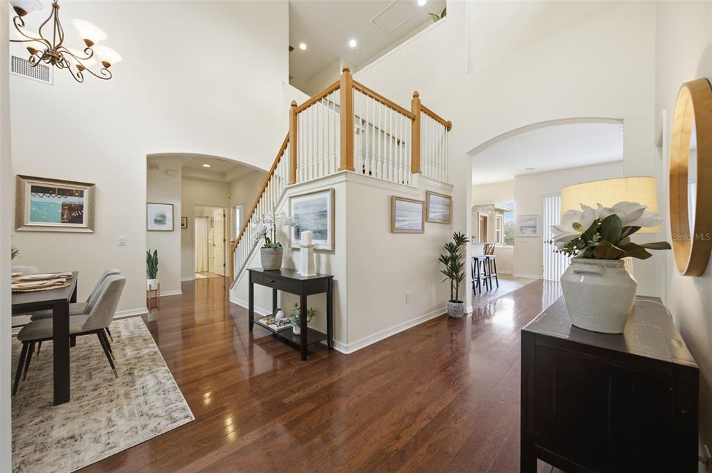 A bright foyer with hardwood floors, a staircase, and an open dining area — 8822 WESTERLAND DRIVE, LAND O LAKES, FL