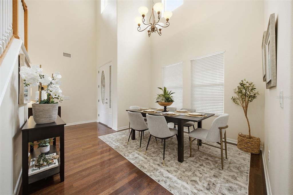 A dining room with a high ceiling, chandelier, dark wood floors, and a six-chair table — 8822 WESTERLAND DRIVE, LAND O LAKES, FL