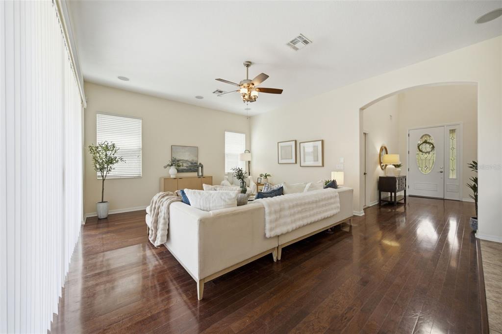 A living room features a white sectional sofa, dark hardwood floors, and a ceiling fan — 8822 WESTERLAND DRIVE, LAND O LAKES, FL