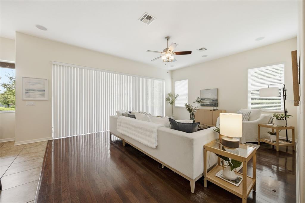 A living room features dark wood flooring, a white sofa, and large vertical window blinds — 8822 WESTERLAND DRIVE, LAND O LAKES, FL