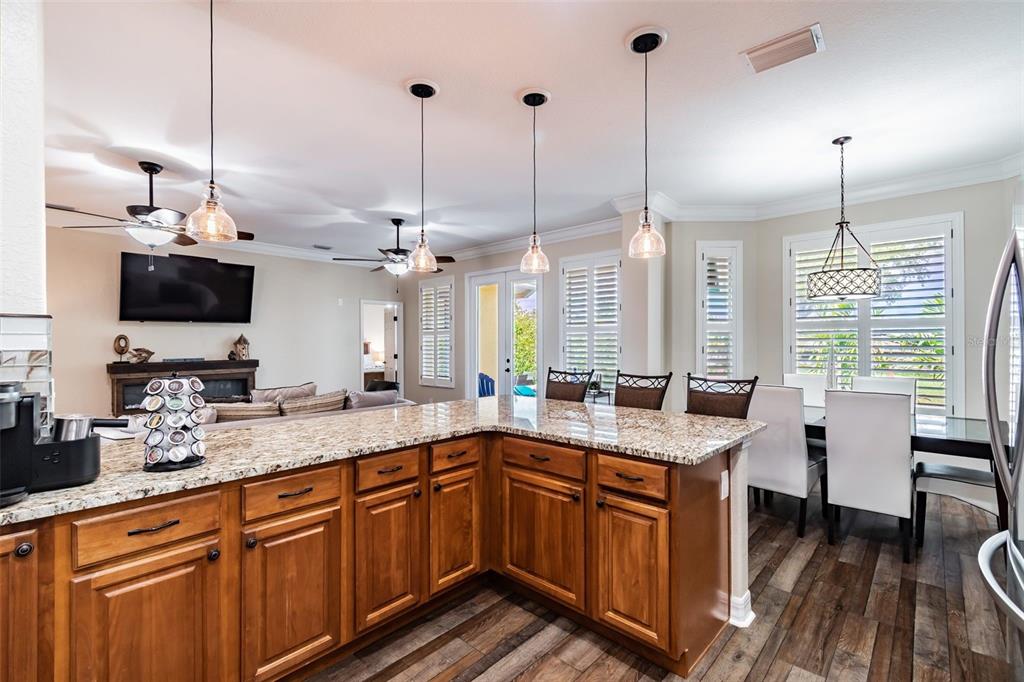 A kitchen with granite countertops and wooden cabinets overlooks a dining area and living room — 539 TREVISO DRIVE, APOLLO BEACH, FL