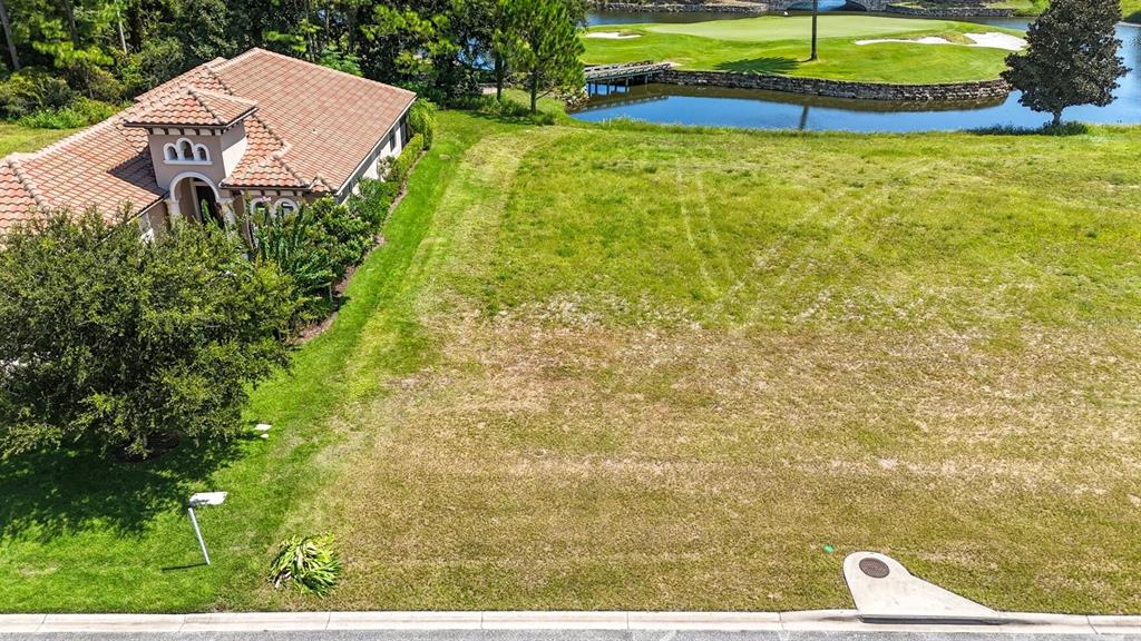 An aerial view shows a vacant residential lot next to a house near a pond — 323 HIBISCUS WAY, PALM COAST, FL