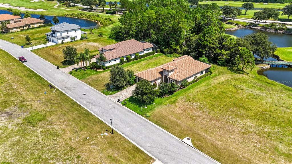 An aerial view shows two single-story houses with tile roofs situated along a paved road — 323 HIBISCUS WAY, PALM COAST, FL