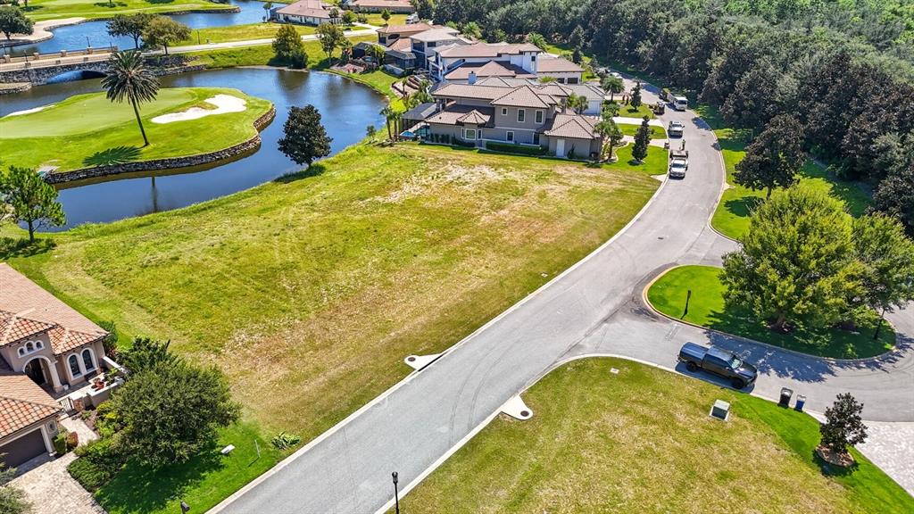 An aerial view shows a vacant residential lot situated between a road and a pond — 323 HIBISCUS WAY, PALM COAST, FL