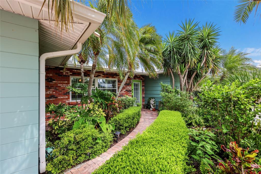 A brick and light blue house exterior features a brick walkway leading to the front door — 5007 BIMINI DRIVE, BRADENTON, FL