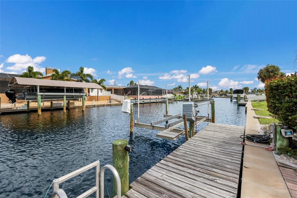 A wooden dock extends into a canal with a boat lift and covered boat slip — 5007 BIMINI DRIVE, BRADENTON, FL