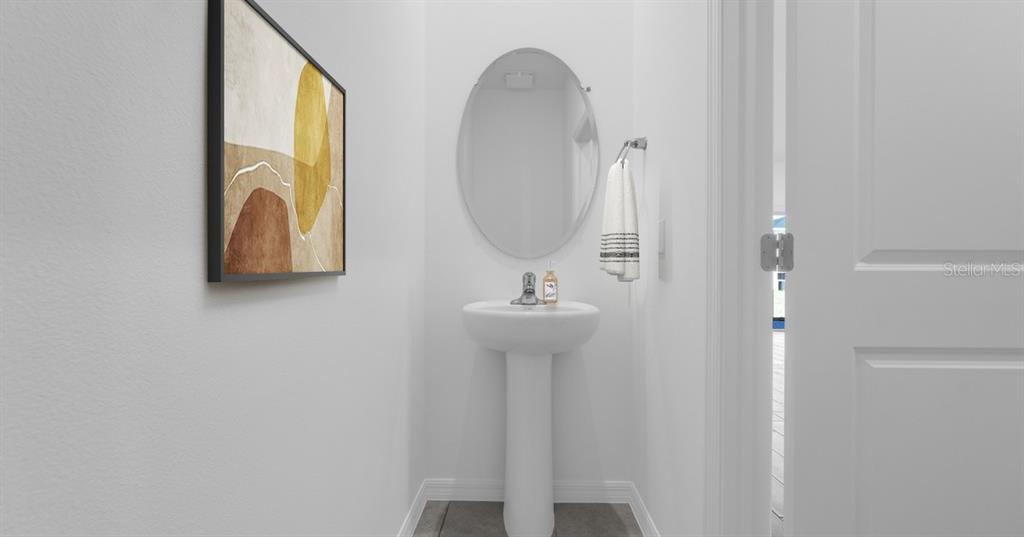 A small powder room features a pedestal sink, an oval mirror, and framed wall art — 4450 RIVER BEACON BOULEVARD, DAVENPORT, FL
