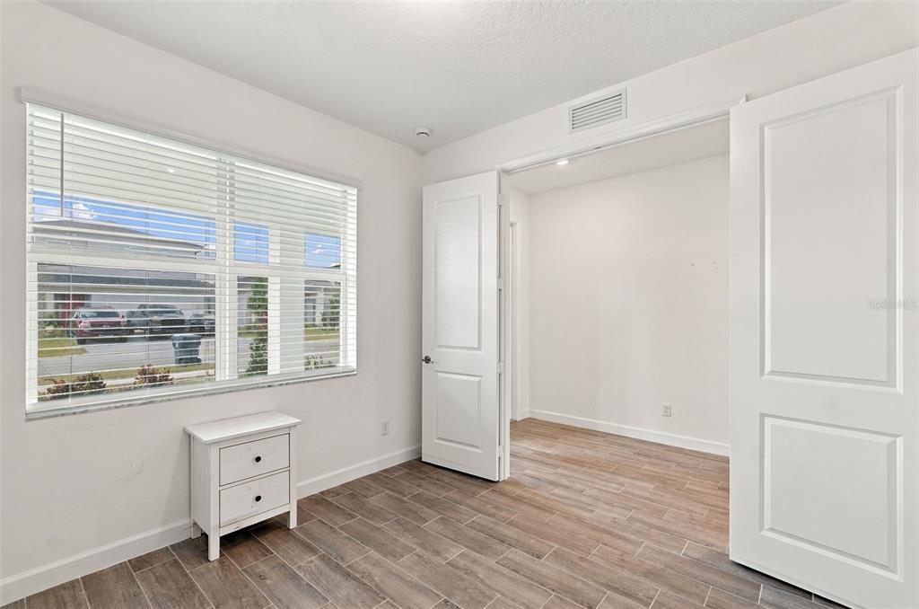 A bedroom with white walls, wood-look tile flooring, a window with blinds, and a closet — 1594 PELICAN POST PLACE, LOXAHATCHEE, FL