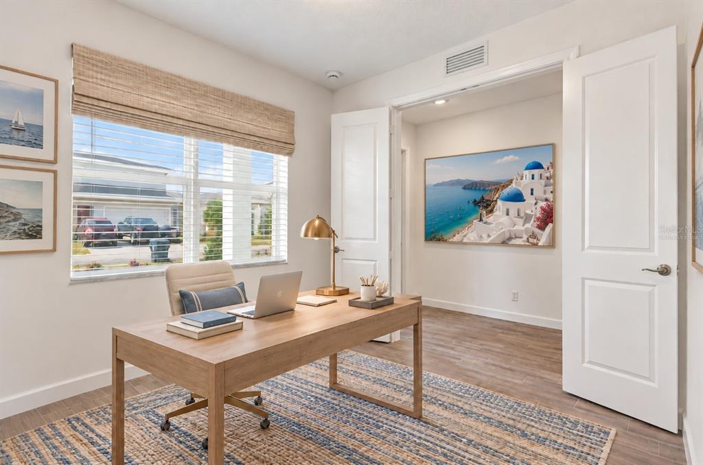 A home office features a wooden desk, a laptop, and a large wall art piece — 1594 PELICAN POST PLACE, LOXAHATCHEE, FL