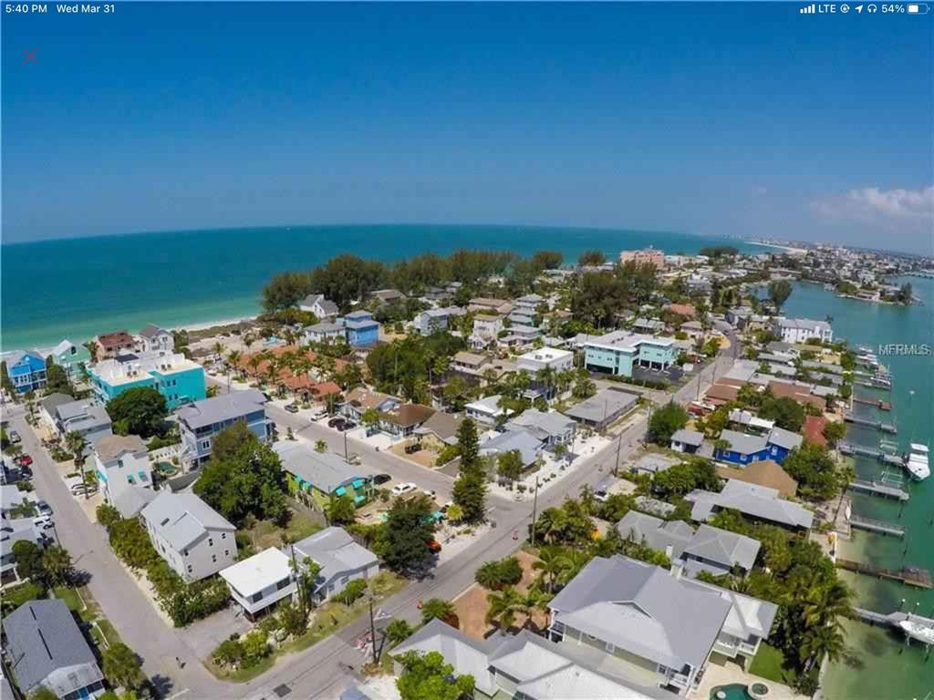An aerial view shows a coastal neighborhood with houses situated between the ocean and bay — 61 81ST AVENUE UNIT 3, TREASURE ISLAND, FL