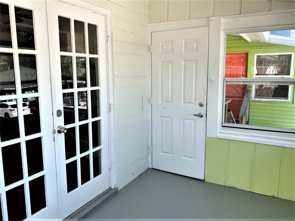 A covered porch features white French doors, a white six-panel door, and a window — 61 81ST AVENUE UNIT 3, TREASURE ISLAND, FL