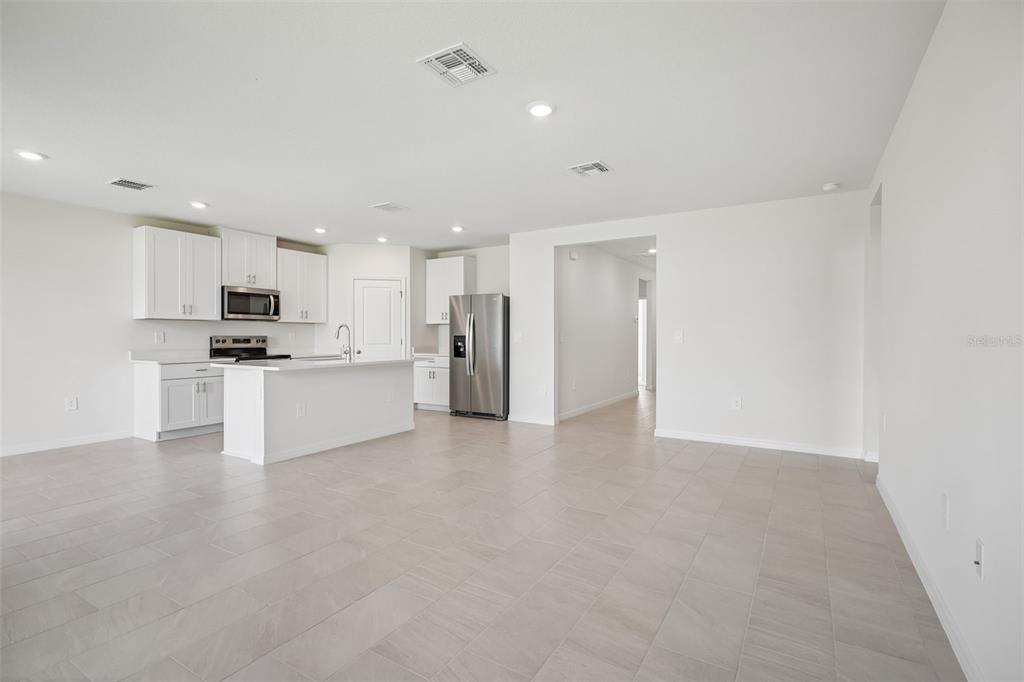 A bright, open-concept kitchen and living area featuring white cabinets, an island, and wood flooring — 1769 FOREST RUN LANE, AUBURNDALE, FL