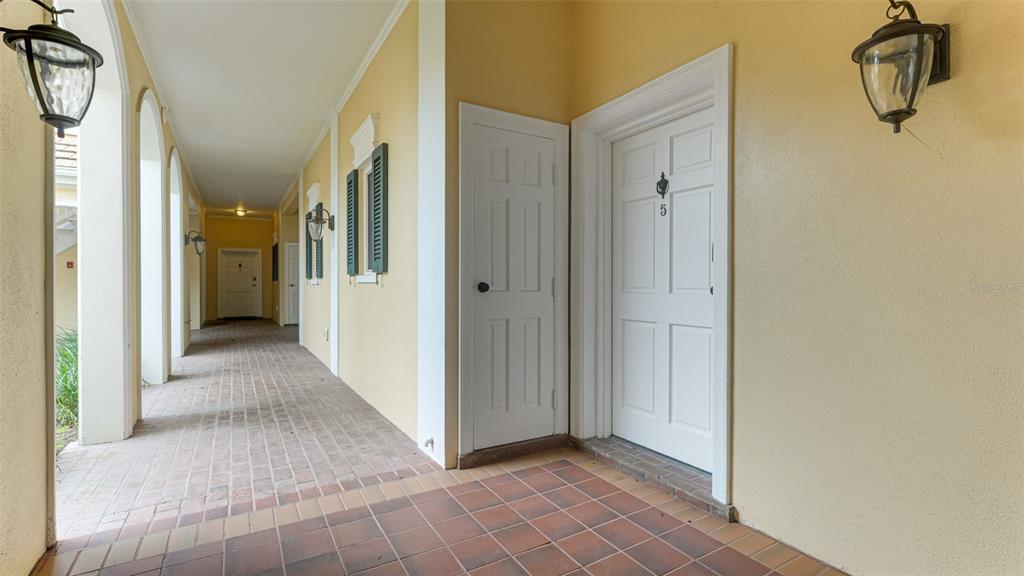 A covered outdoor walkway features a tiled floor, yellow walls, and two white doors — 51 MACEWEN DRIVE UNIT 5, OSPREY, FL