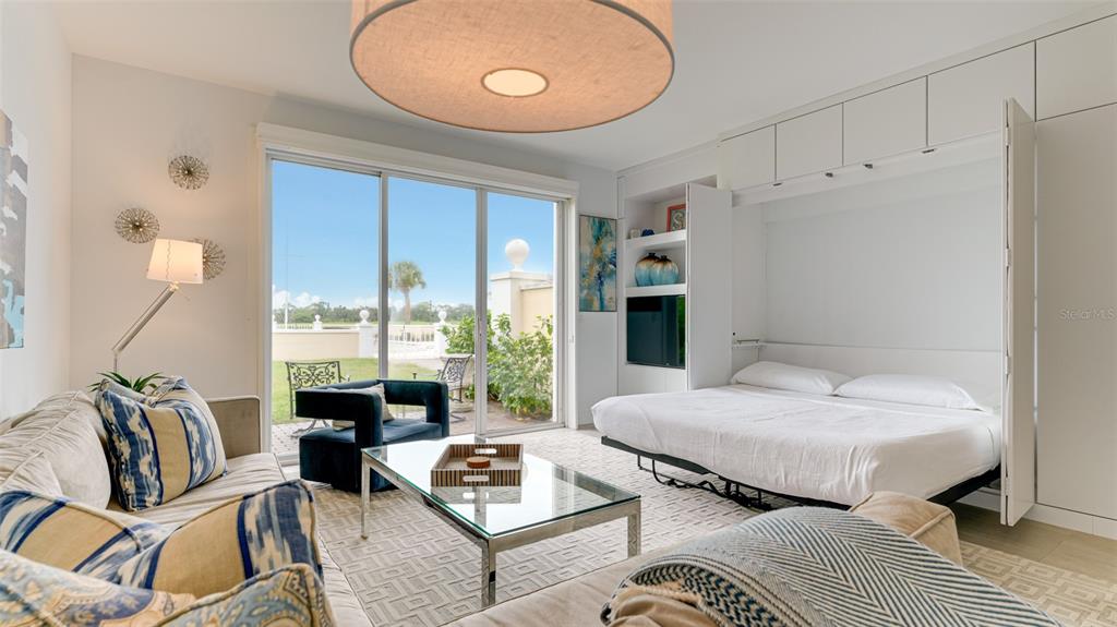 A living room features a fold-down bed, a glass coffee table, and sliding glass doors — 51 MACEWEN DRIVE UNIT 5, OSPREY, FL