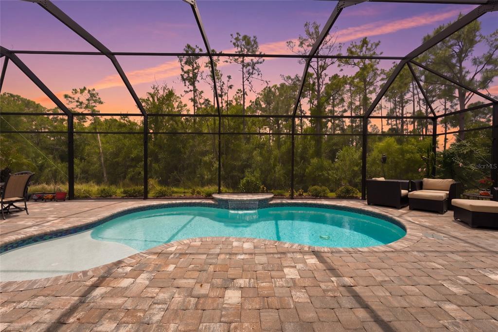 A screened-in patio features a swimming pool with a spillover spa and outdoor seating — 617 MISTIFLOWER CIRCLE, NOKOMIS, FL