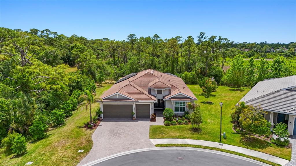 A single-story house with a paved driveway, three-car garage, and landscaped front yard at sunset — 617 MISTIFLOWER CIRCLE, NOKOMIS, FL