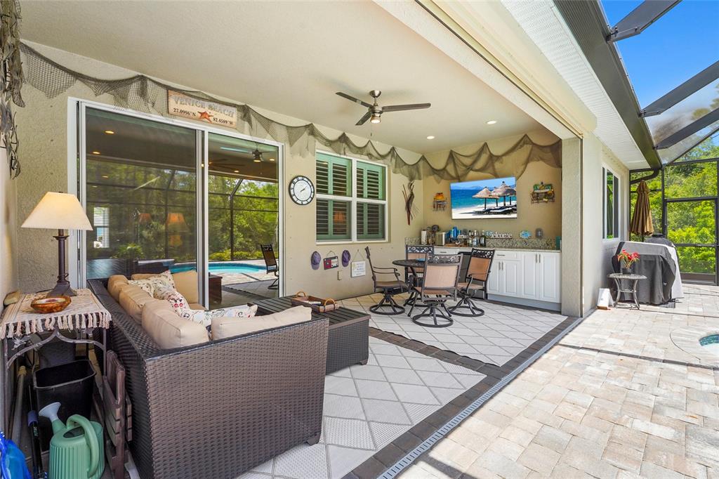 A covered outdoor patio features a seating area, dining set, wet bar, and pool view — 617 MISTIFLOWER CIRCLE, NOKOMIS, FL