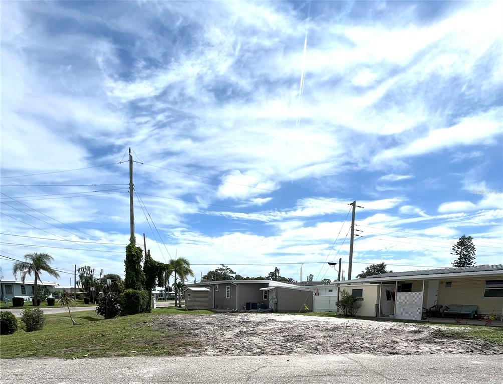 A vacant, sandy residential lot sits in front of a small, one-story house — 6903 E BAYOU LANE, BRADENTON, FL