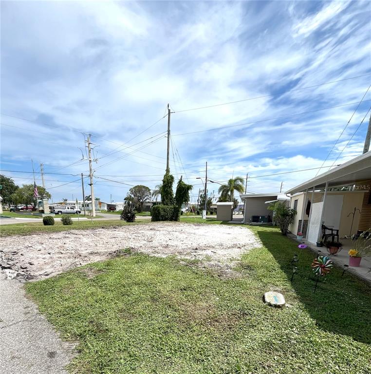 A vacant, sandy lot sits next to a mobile home with a covered porch — 6903 E BAYOU LANE, BRADENTON, FL