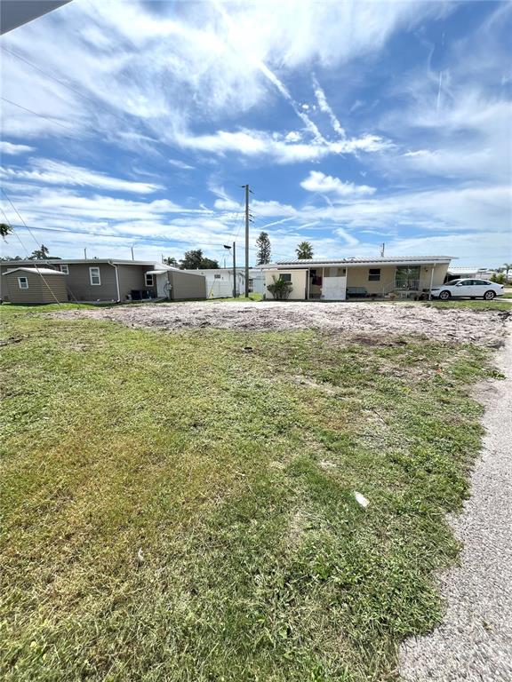 A vacant, grassy lot sits in front of a mobile home and a small shed — 6903 E BAYOU LANE, BRADENTON, FL
