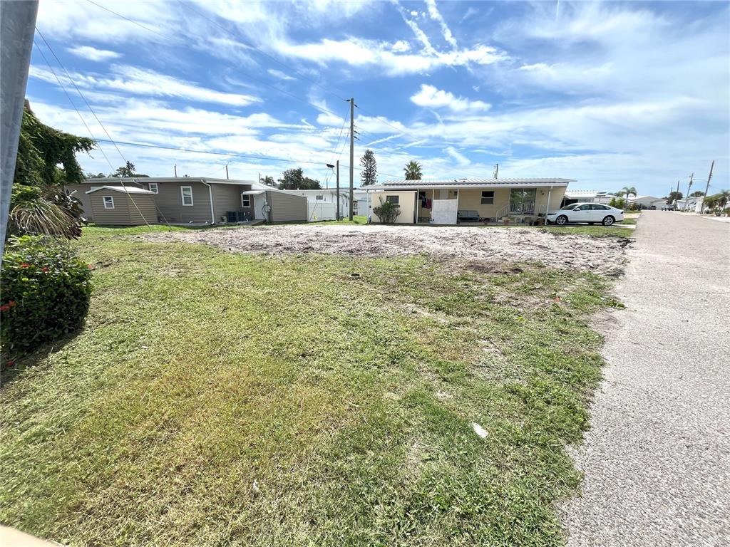 A vacant, dirt-covered lot sits between two single-story residential buildings along a paved road — 6903 E BAYOU LANE, BRADENTON, FL