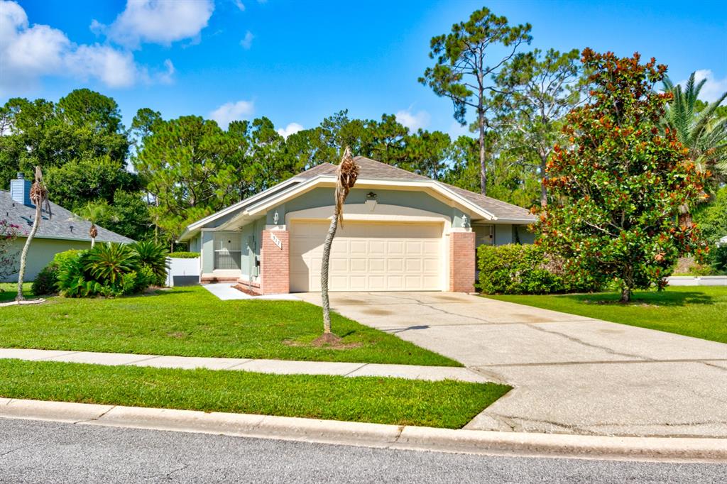 A single-story house with a beige garage door, brick accents, and a concrete driveway — 317 GLENBRIAR CIRCLE, DAYTONA BEACH, FL