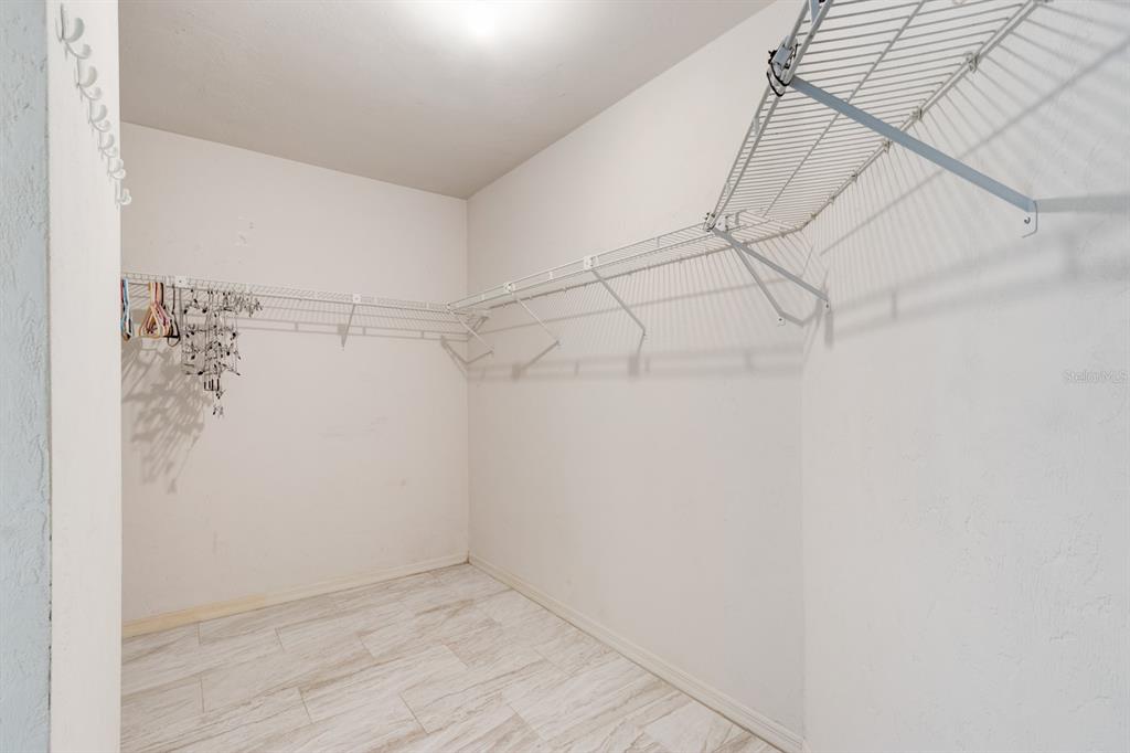 A walk-in closet features white walls, light-colored tile flooring, and wire shelving — 317 GLENBRIAR CIRCLE, DAYTONA BEACH, FL