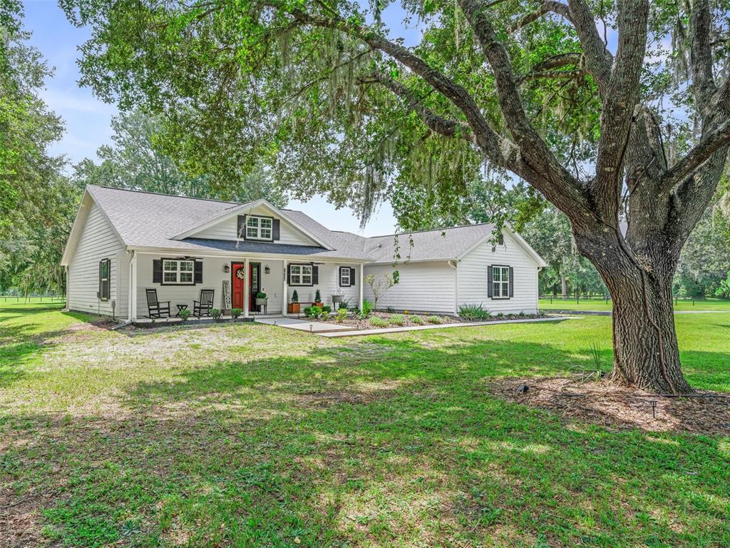 A white single-story house with a red front door sits on a grassy lawn — 1539 SE 34TH WAY, SUMTERVILLE, FL