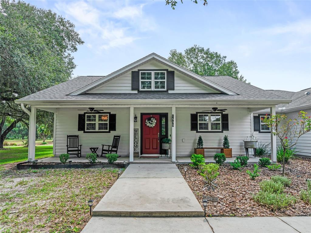 A single-story house with a red front door, covered porch, and light-colored siding — 1539 SE 34TH WAY, SUMTERVILLE, FL