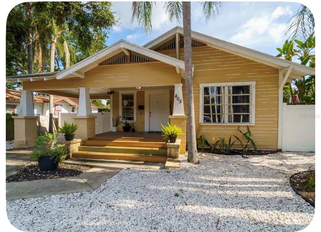 A yellow bungalow with a covered front porch, white trim, and a white gravel yard — 405 E ADALEE STREET, TAMPA, FL