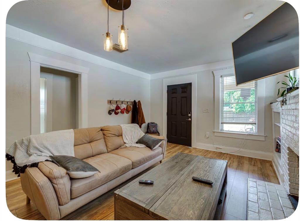 A living room features a tan sofa, wooden coffee table, dark door, and brick fireplace — 405 E ADALEE STREET, TAMPA, FL