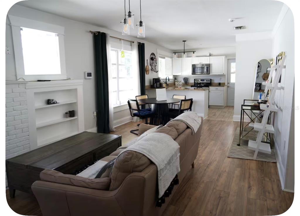 An open-concept living room and kitchen with wood-look flooring, white cabinets, and a dining area — 405 E ADALEE STREET, TAMPA, FL