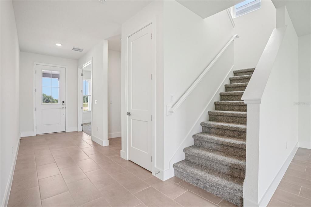 An entryway with tile flooring, a white front door, a closet, and carpeted stairs — 30333 EMERALD FOREST DRIVE, MOUNT DORA, FL