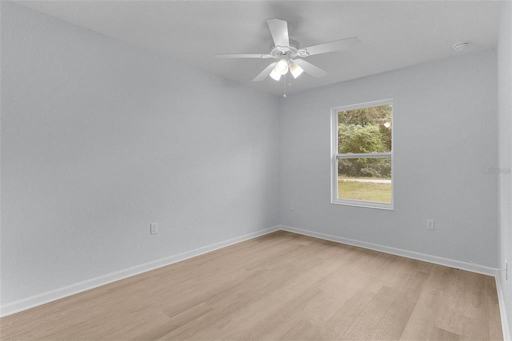 An empty bedroom with light gray walls, wood-look flooring, and a white ceiling fan — 77 FISHER RUN TERRACE, OCKLAWAHA, FL