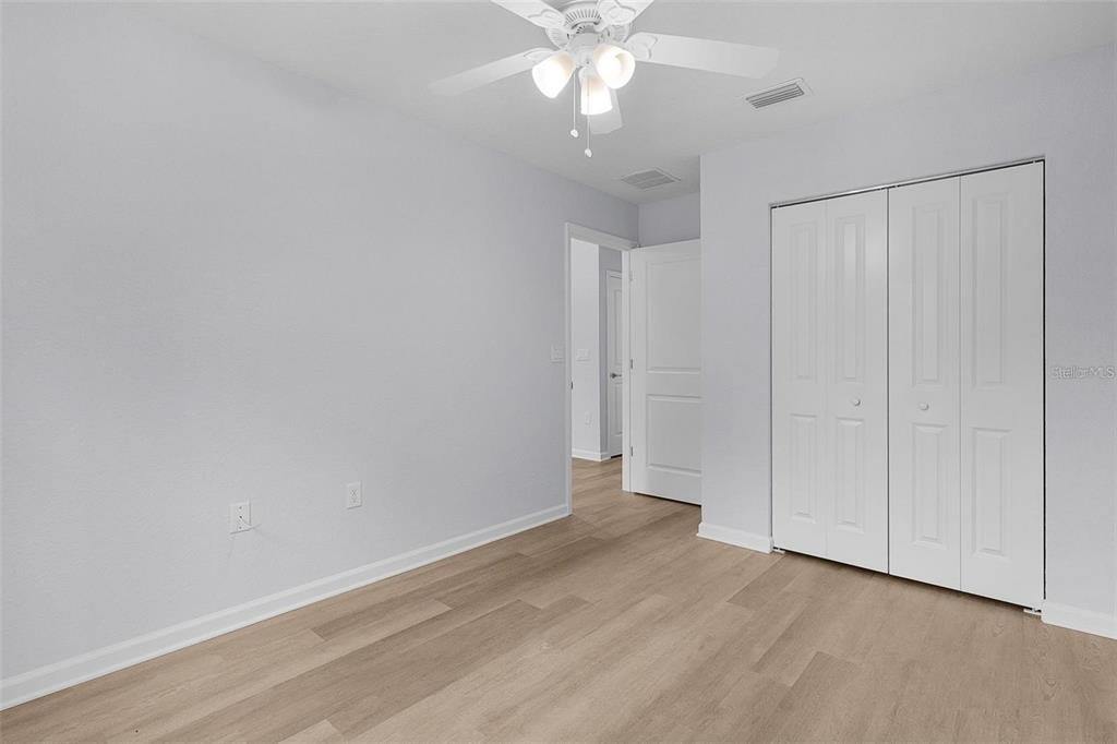 An empty bedroom features light wood-look flooring, white walls, a ceiling fan, and a closet — 77 FISHER RUN TERRACE, OCKLAWAHA, FL