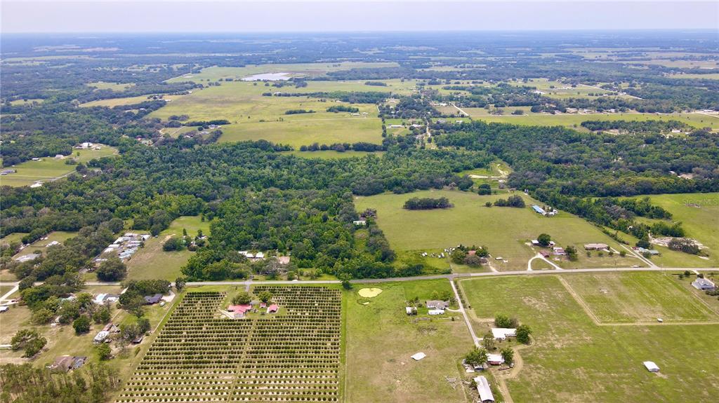 An aerial view shows a large rural property with fields, wooded areas, and scattered buildings — 14435 CURLEY ROAD, DADE CITY, FL