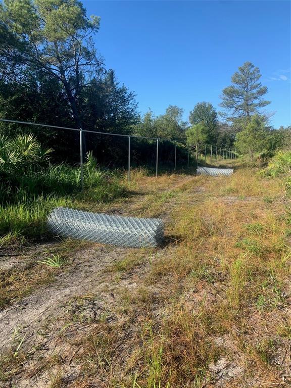 A chain-link fence is being installed along a dirt path in a wooded area — 2701 METRO DRIVE, RUSKIN, FL