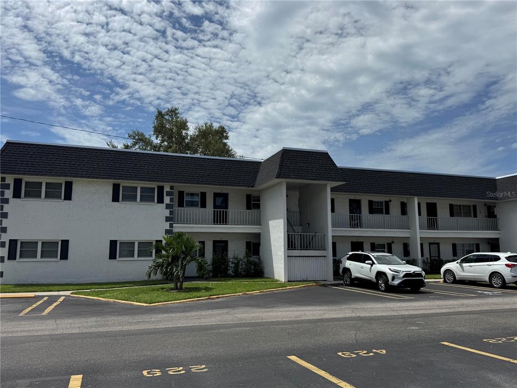 A two-story apartment building with white stucco walls and a dark shingled roof — 204 46TH AVENUE TERRACE W UNIT 411, BRADENTON, FL