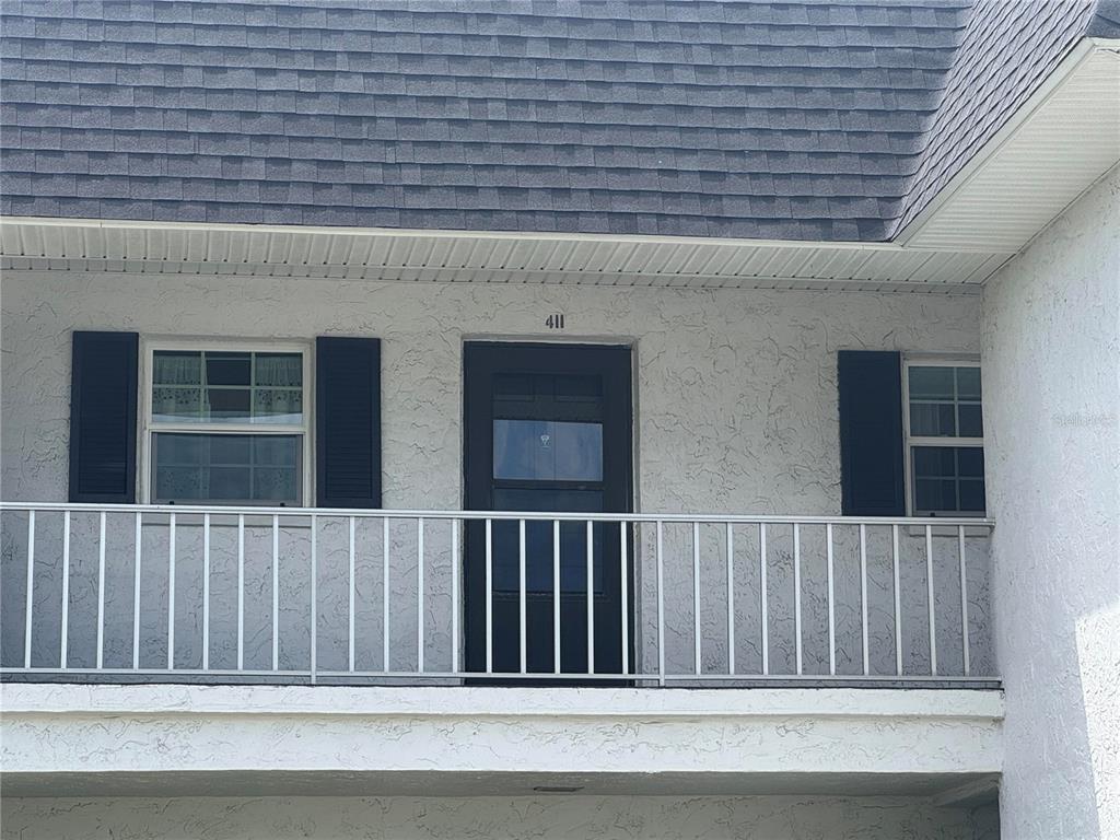 An exterior view shows a second-story balcony with a door labeled 411 and two windows — 204 46TH AVENUE TERRACE W UNIT 411, BRADENTON, FL