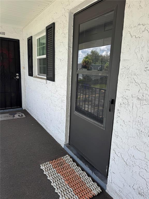 A view of a building exterior showing two doors, a window with shutters, and doormats — 204 46TH AVENUE TERRACE W UNIT 411, BRADENTON, FL