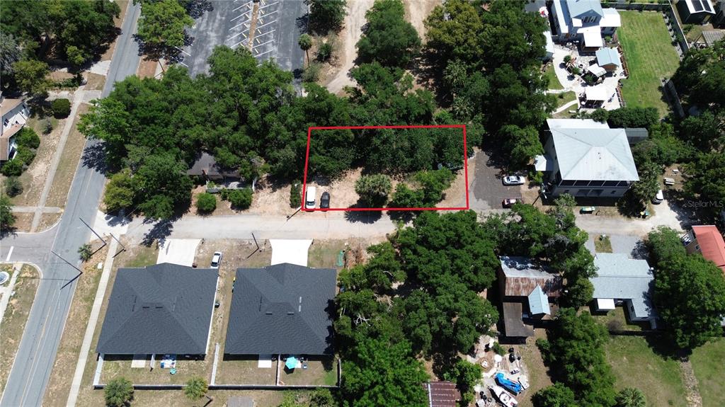 An aerial view shows a rectangular vacant lot outlined in red between existing residential properties — DEWITT COURT, EUSTIS, FL