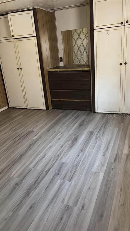 A bedroom features wood-paneled walls, built-in white cabinets, a dark dresser, and light wood flooring — 212 SUNSET DRIVE, LAKE ALFRED, FL