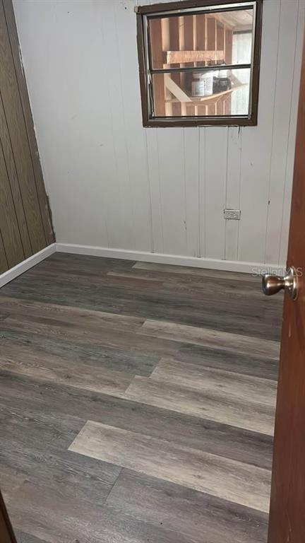 A small room features wood-look laminate flooring, white paneling, and a window overlooking a shed — 212 SUNSET DRIVE, LAKE ALFRED, FL