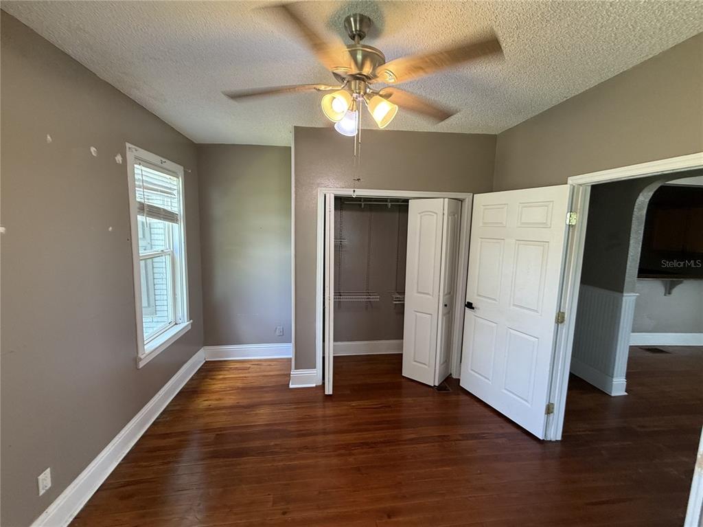 A bedroom with hardwood floors, a ceiling fan, a closet, and a doorway to another room — 1115 KELLER ROAD, FORT MEADE, FL