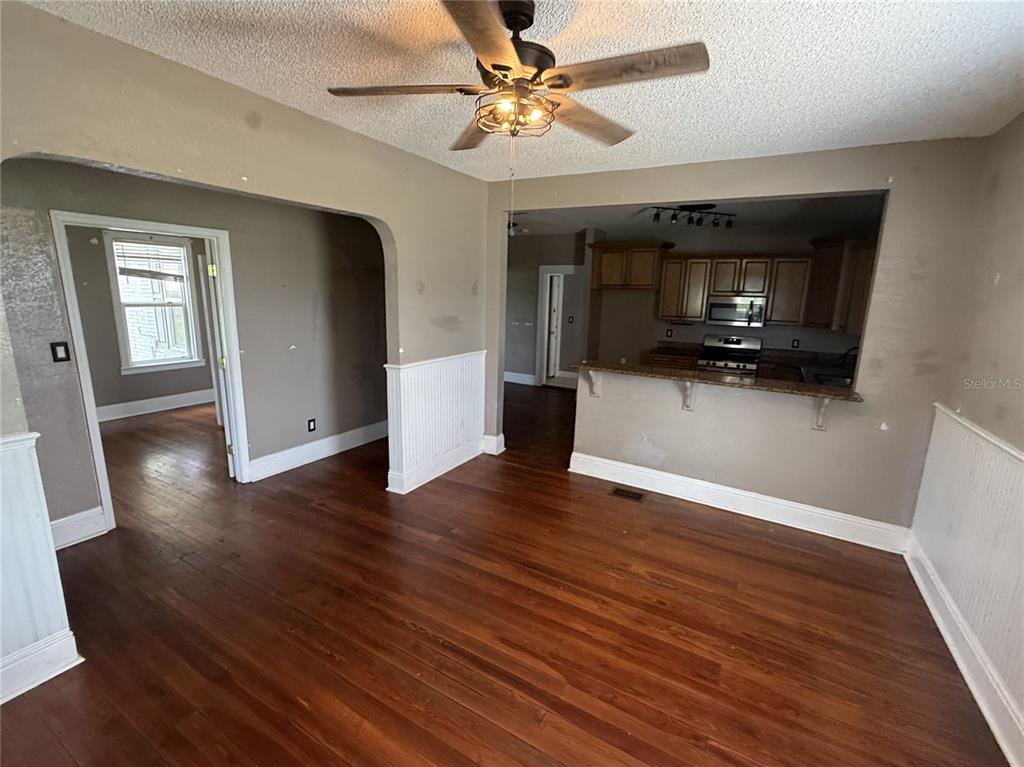 A living room with hardwood floors and a ceiling fan opens into a kitchen area — 1115 KELLER ROAD, FORT MEADE, FL