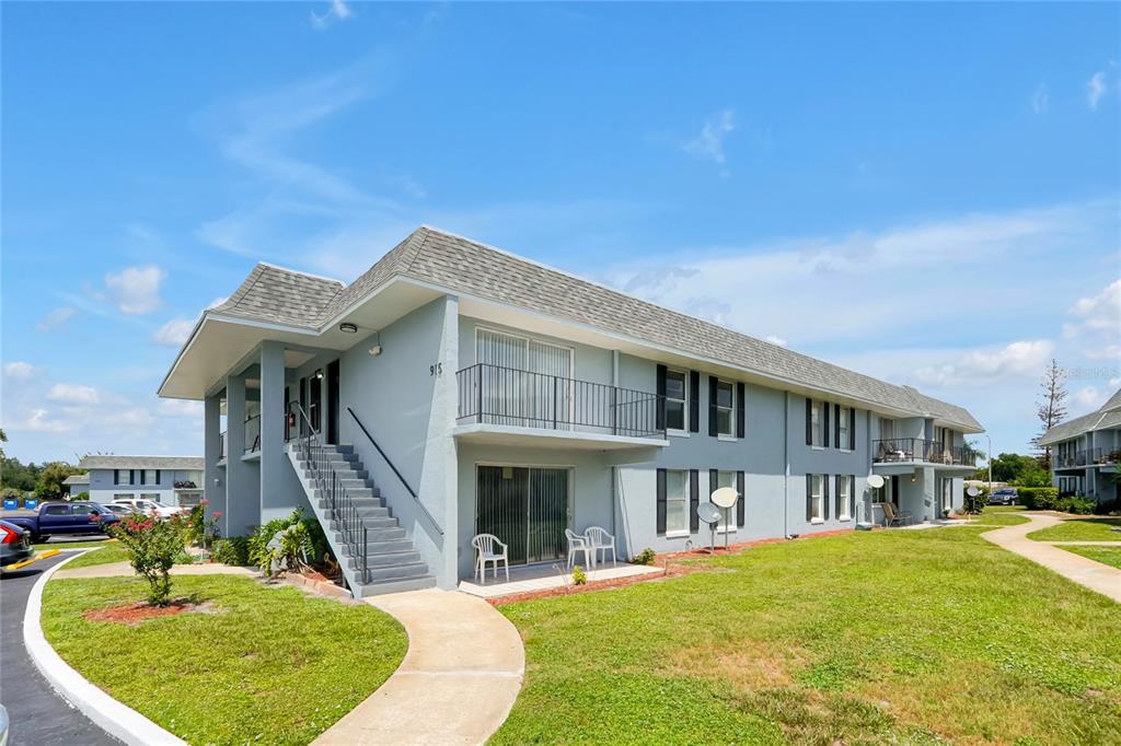 A two-story apartment building with light blue siding, a concrete staircase, and a grassy lawn — 915 W OAK RIDGE ROAD UNIT B, ORLANDO, FL