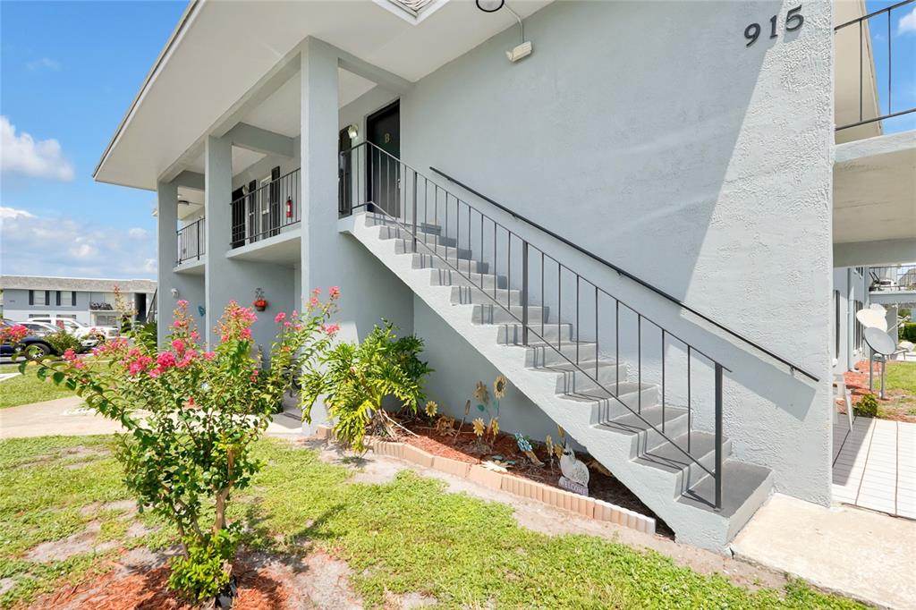 An exterior view of a two-story apartment building with an outdoor staircase and landscaping — 915 W OAK RIDGE ROAD UNIT B, ORLANDO, FL